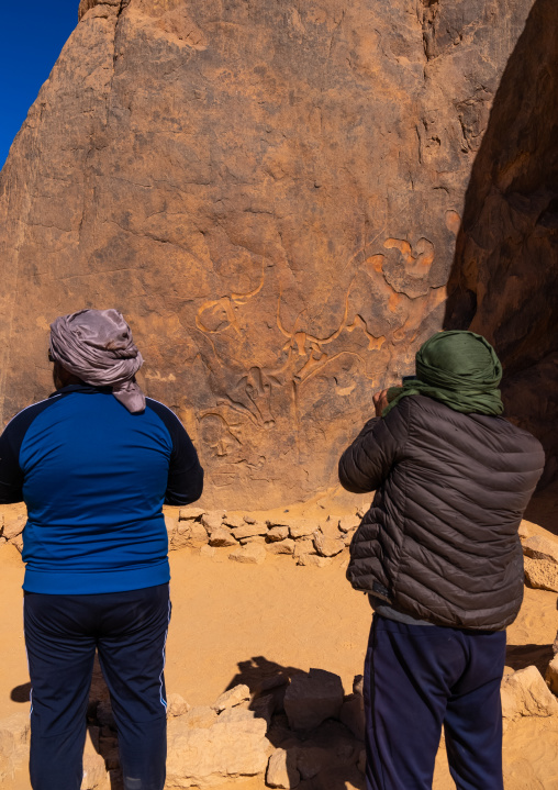 Tourists visiting la vache qui pleure rock carving, North Africa, Erg Admer, Algeria