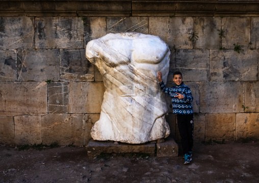 Boy near the torso of Jupiter statue, North Africa, Djemila, Algeria