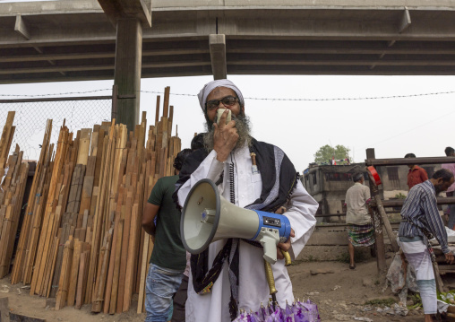 A bangladeshi religious man speaks in a loudspeaker along a rail track, Dhaka Division, Dhaka, Bangladesh