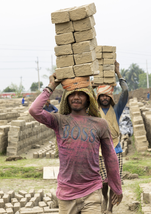 A bangladeshi man carries bricks on his head at a brick factory, Sylhet Division, Bahubal, Bangladesh