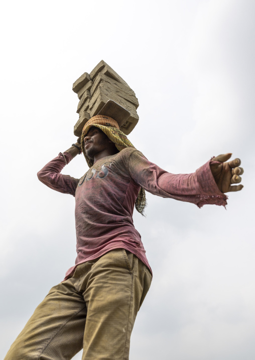 A bangladeshi man carries bricks on his head at a brick factory, Sylhet Division, Bahubal, Bangladesh