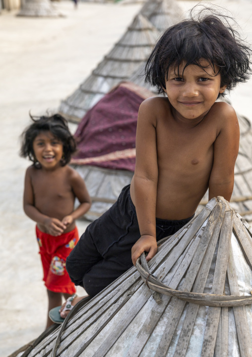 Bangladeshi children and mounds of rice with giant hat-shaped bamboo cones, Chittagong Division, Ashuganj, Bangladesh