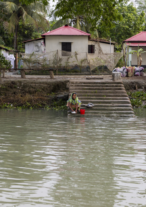 Bangladeshi woman washing cooking dishes in a river in Sundarbans, Barisal Division, Banaripara, Bangladesh