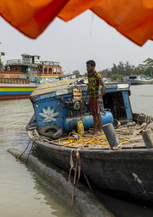 Bangladeshi men attaching a tree trunk to their boat, Barisal Division, Nesarabad, Bangladesh