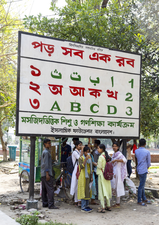 Bangladeshi students under a billboard promoting muslim education, Khulna Division, Jessore, Bangladesh