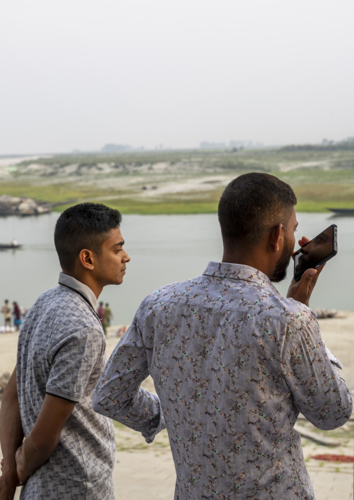 Bangladeshi young men using mobile phone at Kalitola ghat, Rajshahi Division, Sariakandi, Bangladesh