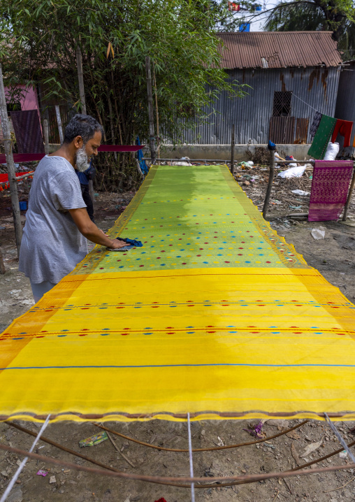 Bangladeshi man putting wax on fabric, Dhaka Division, Rupganj, Bangladesh