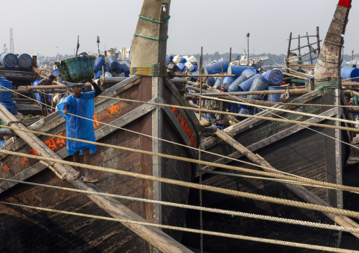 A bangladeshi porter carries a load from a trawler at the morning fish market, Chittagong Division, Chittagong, Bangladesh