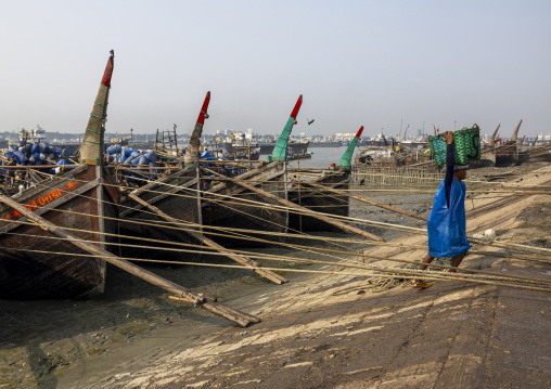 A bangladeshi porter carries a load from a trawler at the morning fish market, Chittagong Division, Chittagong, Bangladesh