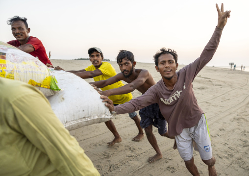 Bangladeshi men pushing a cart full of fishes bags on the beach, Chittagong Division, Cox's Bazar Sadar, Bangladesh