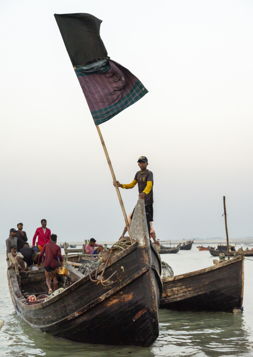 Bangladeshi man holding a flag on a moon fishing boat, Chittagong Division, Cox's Bazar Sadar, Bangladesh