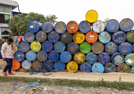 Bangladeshi man passing near multi colored barrels, Chittagong Division, Rangamati Sadar, Bangladesh