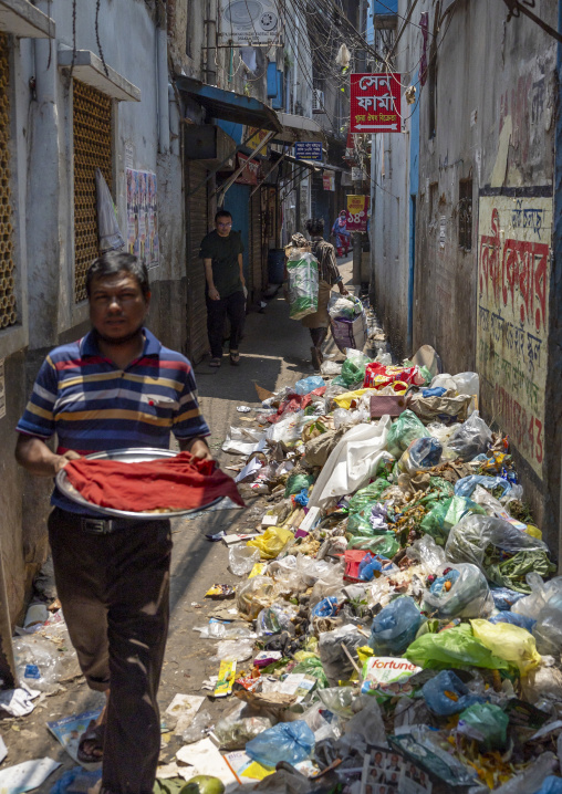 Bangladeshi man walking in a narrow street full of garbages, Dhaka Division, Dhaka, Bangladesh