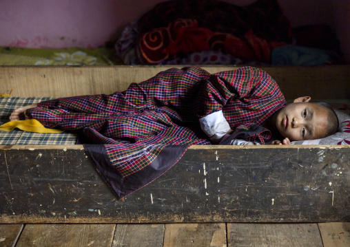 Bhutanese novice monk resting in Nyenzer Lhakhang dormitory, Thedtsho Gewog, Wangdue Phodrang, Bhutan