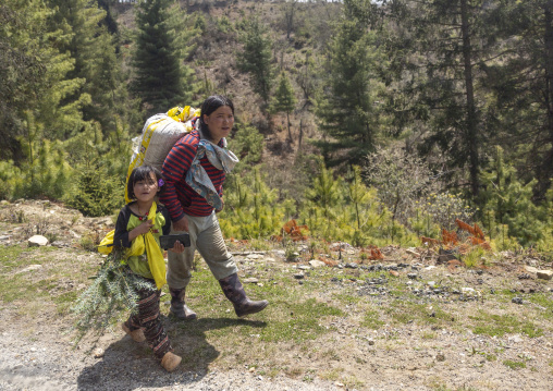 Bhutanese mother carrying bag and her daughter walking, Chhoekhor Gewog, Bumthang, Bhutan