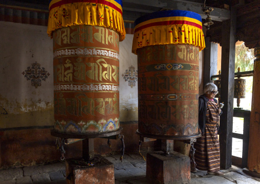 Bhutanese woman spinning giant prayer wheels in Jamphel Lhakhang, Chhoekhor Gewog, Bumthang, Bhutan