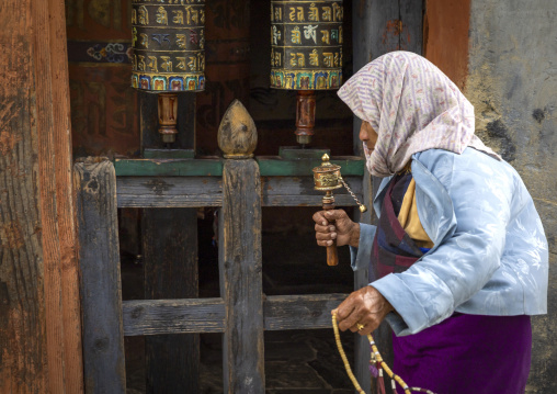 Bhutanese woman with prayer wheels in Jamphel Lhakhang, Chhoekhor Gewog, Bumthang, Bhutan