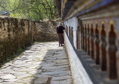 Bhutanese woman spiniing a prayer wheels in Ogyen Choling, Bumthang, Ogyen Choling, Bhutan