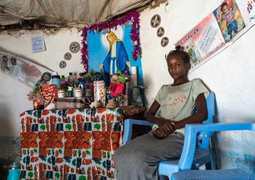 Eritrean Kunama tribe girl in front of a virgin mary poster in a home, Gash-Barka, Barentu, Eritrea