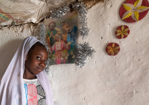 Eritrean Kunama tribe teenage girl in front of a religious poster, Gash-Barka, Barentu, Eritrea