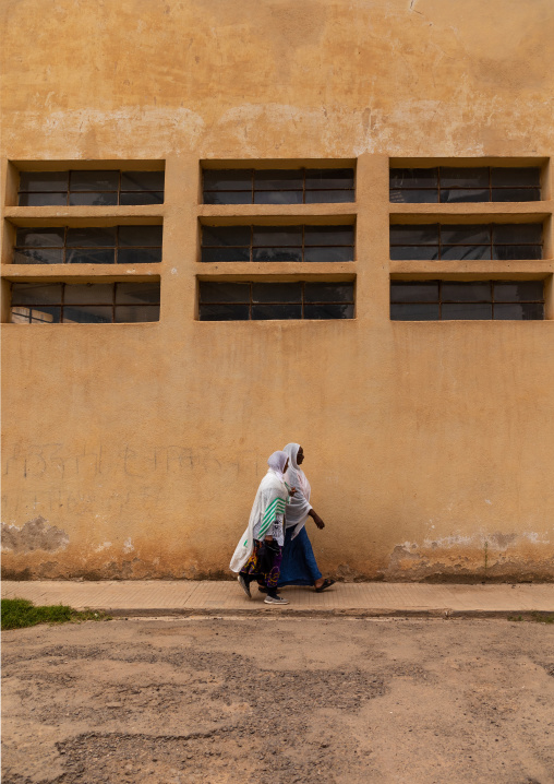 Eritrean women passing in front the swimming pool built during the italian colonial times, Central region, Asmara, Eritrea