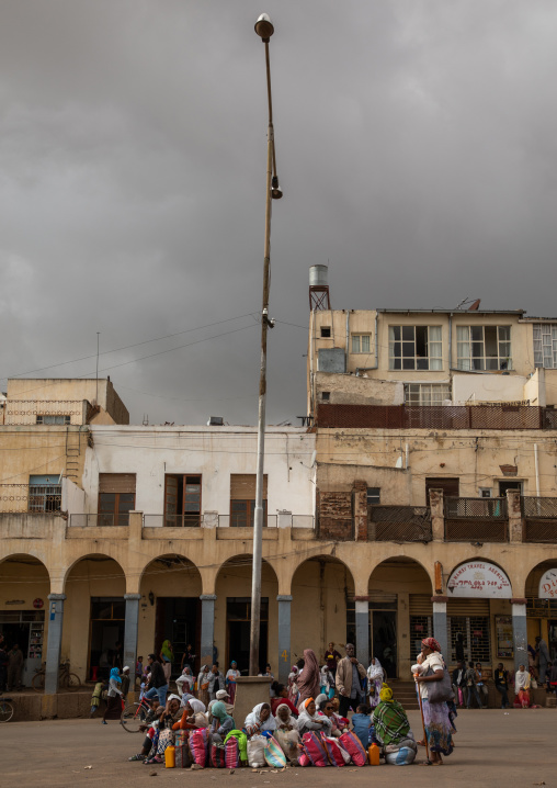 Eritrean people waiting in front of old art deco style buildings with arches from the italian colonial times, Central region, Asmara, Eritrea