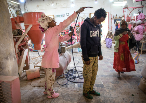 Workers using compressed air to remove dust from their clothes in a mill, Central region, Asmara, Eritrea