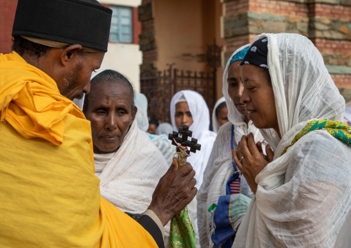 Eritrean women kissing the cross of a priest in enda mariam orthodox cathedral, Central region, Asmara, Eritrea