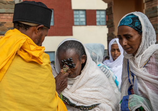 Eritrean women kissing the cross of a priest in enda mariam orthodox cathedral, Central region, Asmara, Eritrea