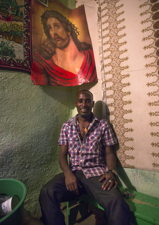 Eritrean man standing in front of a jesus poster, Central Region, Asmara, Eritrea