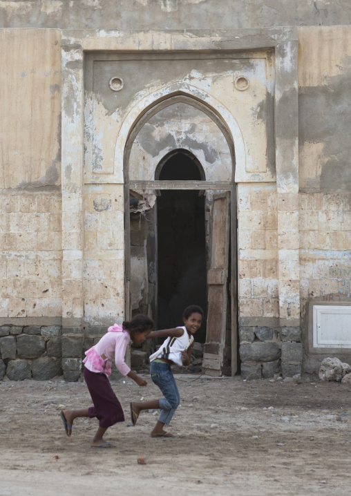 Eritrean girls running in front of an ottoman door, Northern Red Sea, Massawa, Eritrea