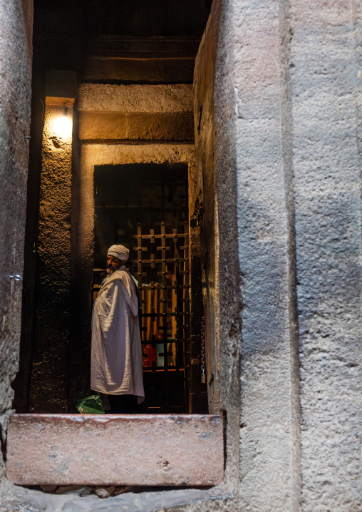 Ethiopian priest standing at the entrance of a rock-hewn church, Amhara Region, Lalibela, Ethiopia