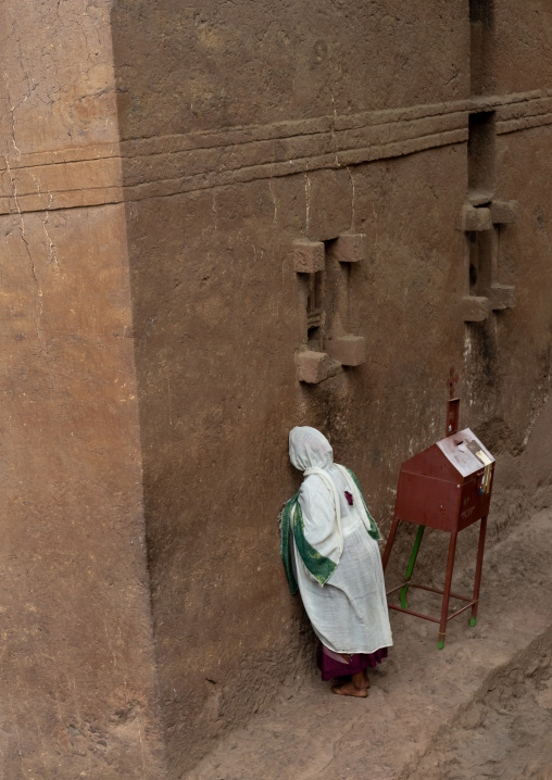 Ethiopian woman pilgrim praying in a rock-hewn church, Amhara Region, Lalibela, Ethiopia