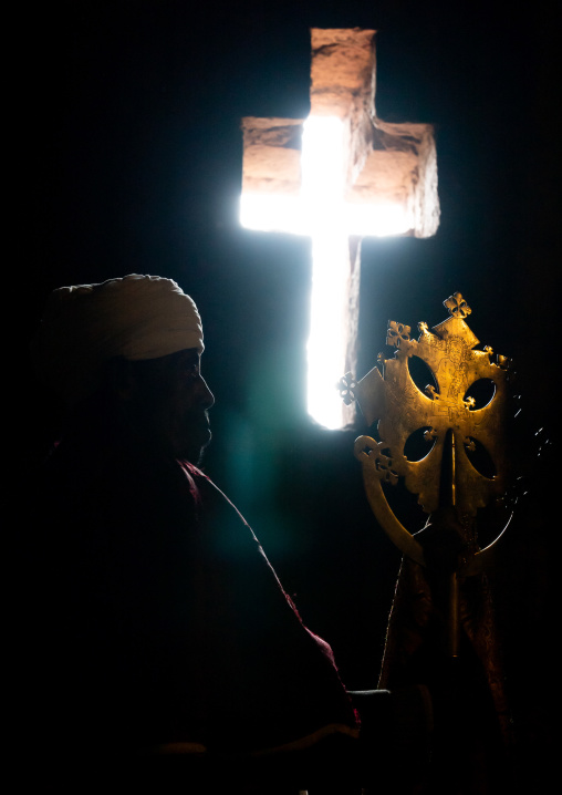 Ethiopian orthodox priest holding a cross inside a rock-hewn church, Amhara Region, Lalibela, Ethiopia