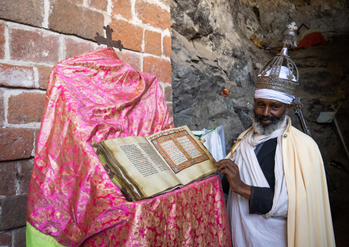 Ethiopian orthodox priest with an old bible in nakuto lab rock church, Amhara Region, Lalibela, Ethiopia