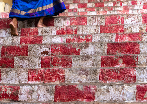 Indian woman on a red and white stairs in a temple, Tamil Nadu, Chettinad, India