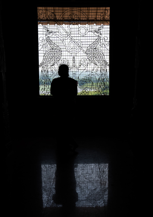 People silhouettes in front of artistic iron work window, Tamil Nadu, Chettinad, India