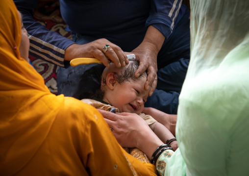 Man shaving the head of a baby in Makhdoom Sahib Shrine, Jammu and Kashmir, Srinagar, India