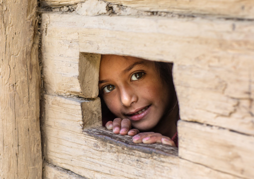 Gujjar Bakerwal girl looking through a hole in a house, Jammu and Kashmir, Kangan, India