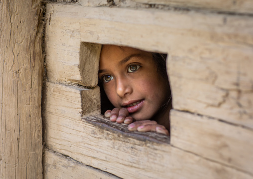 Gujjar Bakerwal girl looking through a hole in a house, Jammu and Kashmir, Kangan, India