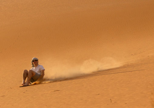 Tourist making sandboarding in the Rub al Khali dunes desert, Najran Province, Thar, Saudi Arabia