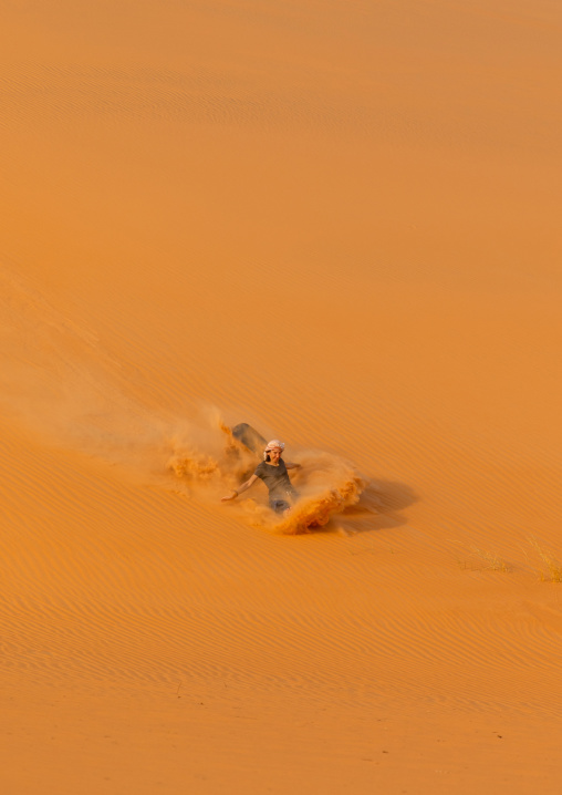 Tourist making sandboarding in the Rub al Khali dunes desert, Najran Province, Thar, Saudi Arabia