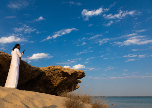 Saudi man texting with his phone in front of the sea, Jazan Province, Farasan, Saudi Arabia