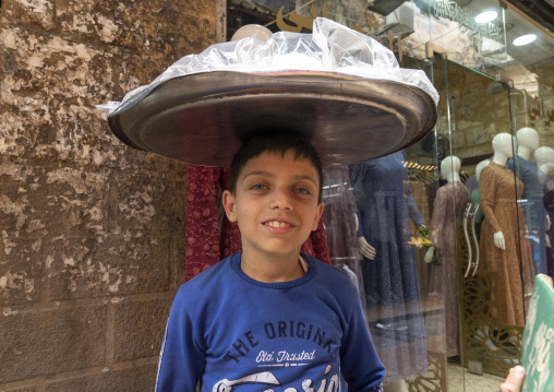 Young syrian boy carrying food on his head in the souk, North Governorate, Tripoli, Lebanon