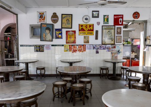 Empty restaurant with vintage enameled advertising plate and posters on the wall, Penang island, George Town, Malaysia