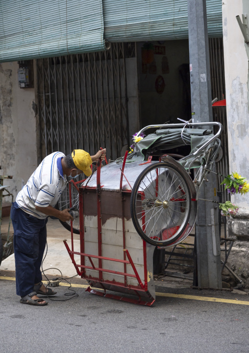 Mechanic repairing a rickshaw in the street, Penang island, George Town, Malaysia