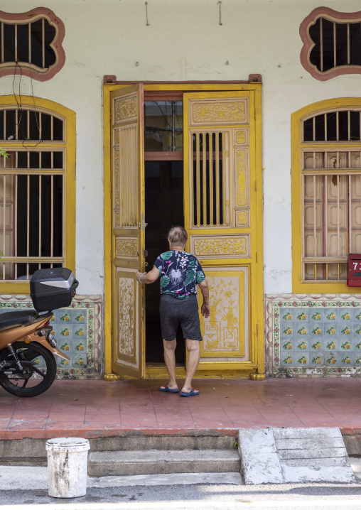 Old woman entering an heritage house in the Unesco World Heritage old town, Penang island, George Town, Malaysia