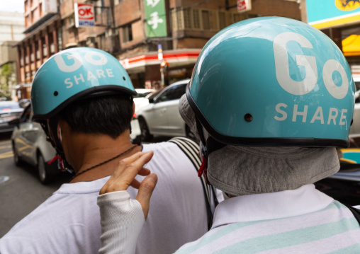 Taiwanese couple riding a go share scooter, Zhongzheng District, Taipei, Taiwan