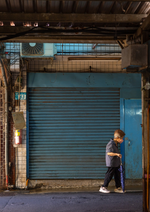 Taiwanese senior woman walking in the old quarter, New Taipei, Tamsui, Taiwan