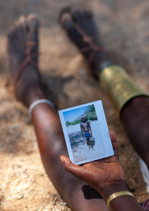 Mucubal tribe woman holding a polaroid of herself, Namibe Province, Virei, Angola